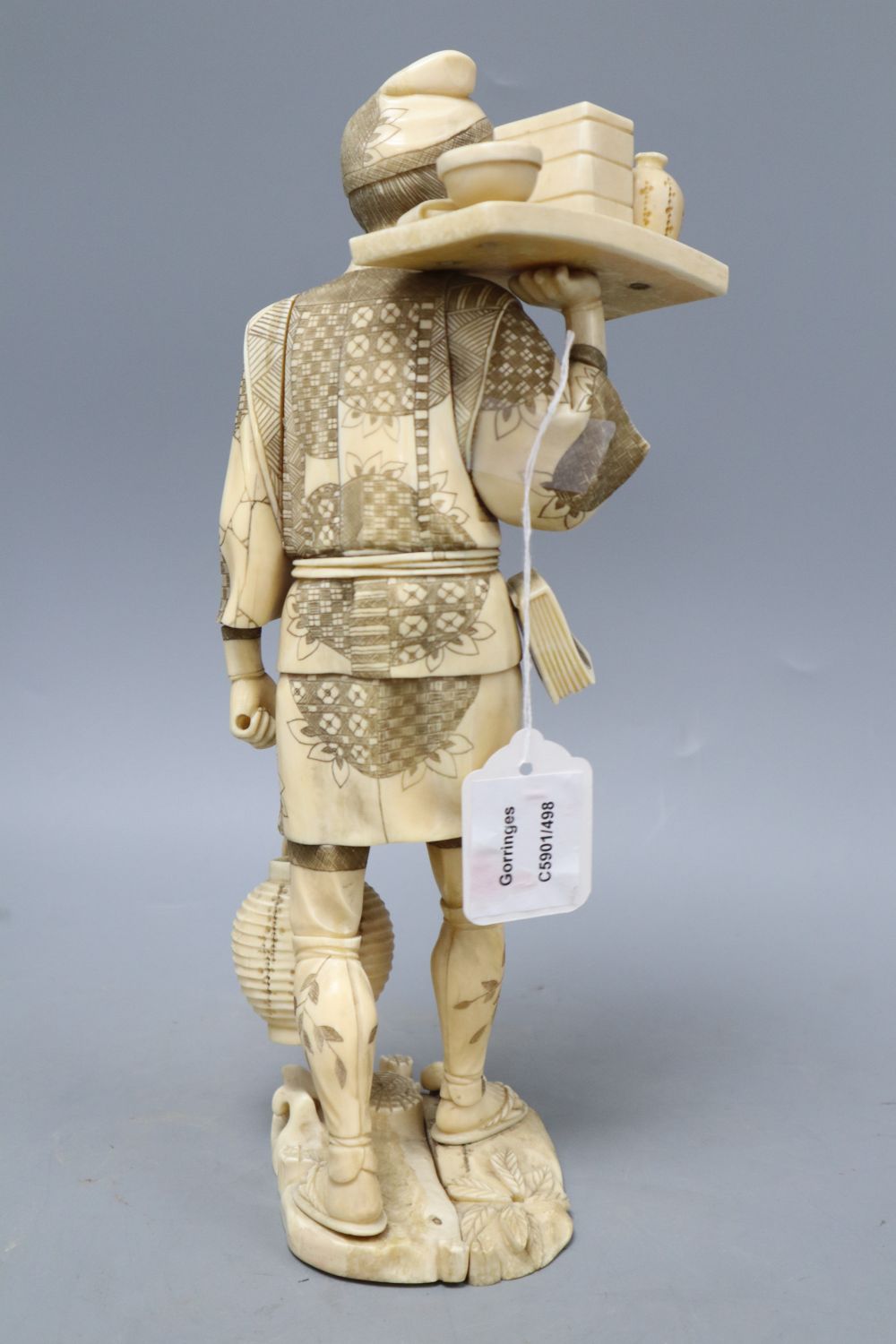 A Japanese Meiji walrus ivory figure of a tradesman, height 32cm